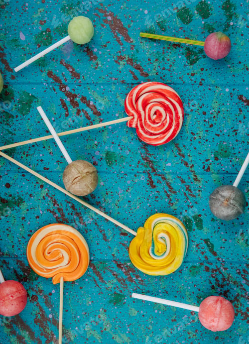 Preview: top view of colorful lollipop candies scattered on blue background