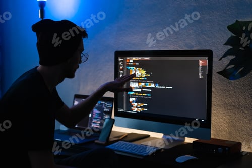 Preview: Young man mobile developer writes program code on a computer, programmer work in home office.
