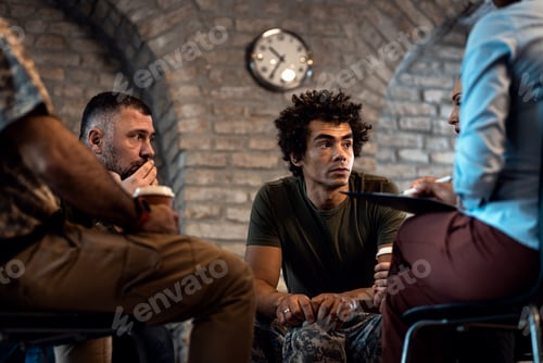 Preview: Group of diverse veterans talking during PTSD support group.