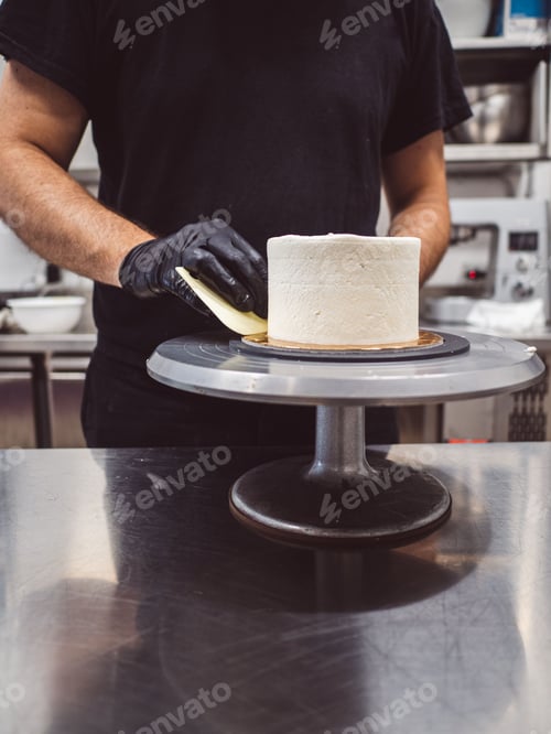 Preview: chef cake smoothing a frosted cake with buttercream with spatula and utensils