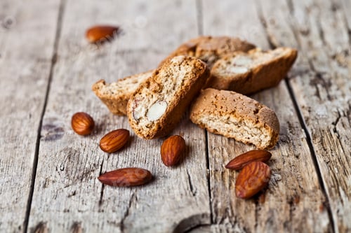 Preview: Fresh homemade Italian cookies cantuccini heap and almond seeds on ructic wooden table.