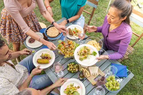 Preview: Top view of people serving food and drinks in a wooden teal table. Getting together concept.