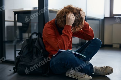 Preview: Exhausted teenager sitting on floor in coworking office