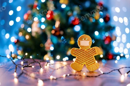 Preview: Cookie-man in a mask on a table with luminous garlands near the Christmas tree. Blur