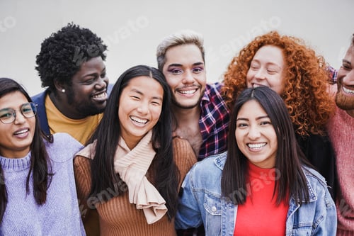 Preview: Group of happy multiethnic people hugging each other outdoor while smiling on camera