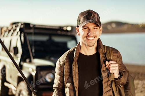 Preview: Young fisherman standing near his car and holding fishing equipment