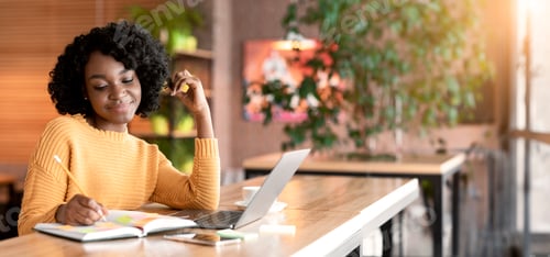 Preview: Dreamy black girl writing down thoughts, spending time at cafe