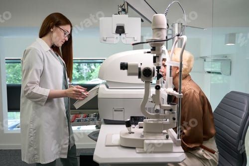 Preview: Young doctor examines the eyes of a middle-aged lady