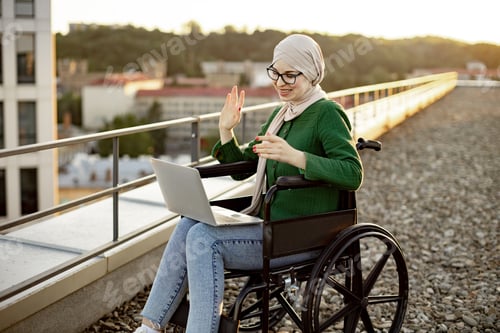 Preview: Female in wheelchair making video call via laptop outdoors