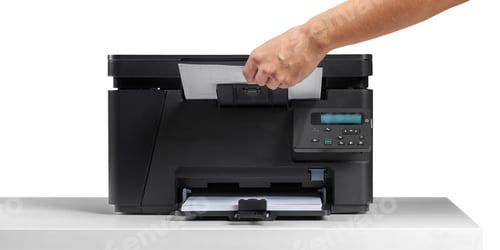 Preview: Hand placing paper in a printer at a desk during a work session inside an office