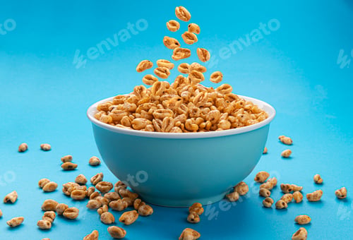Preview: Falling puffed wheat cereal in bowl on blue background