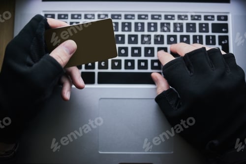 Preview: Shot of an unidentifiable criminal using a laptop to hack into a credit account
