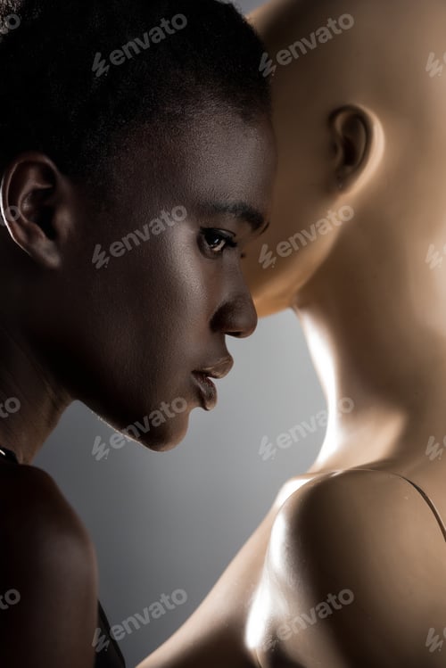 Preview: profile portrait of beautiful young african american woman standing near dummy on black
