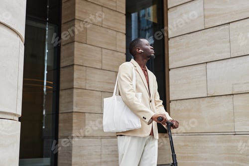 Preview: Young modern businessman in elegant attire holding by scooter handles