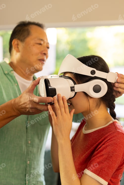 Preview: Adjusting VR headset, father helping daughter experience virtual reality at home