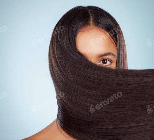 Preview: A hispanic brunette woman with long lush beautiful hair posing and smiling against a grey studio ba