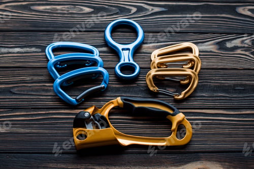 Preview: Looking good. Isolated photo of climbing equipment. Parts of carabiners lying on the wooden table