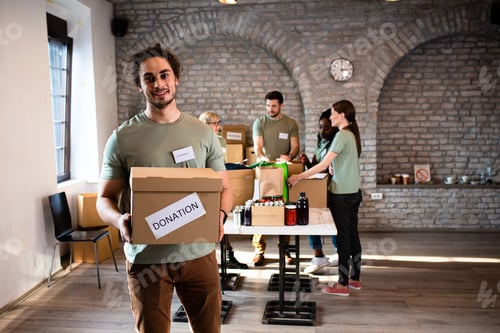 Preview: Portrait of male volunteer holding a box with donation.