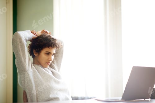Preview: young woman looking at laptop computer screen and thinking