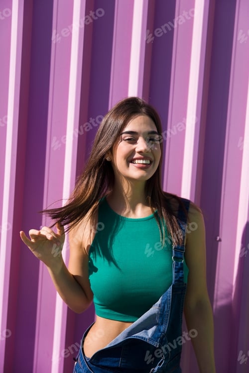 Preview: Trendy young woman standing by the pink wall
