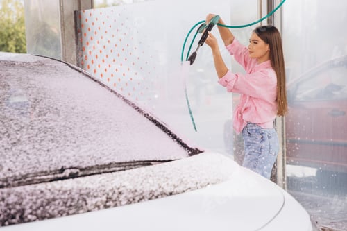 Preview: Young Woman Washing Car With High-Pressure Hose at Car Wash