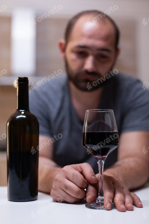 Preview: Close up of glass with wine for lonely man in kitchen