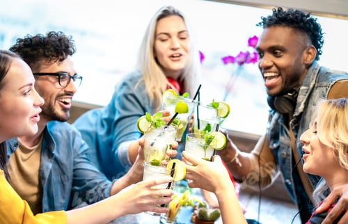 Preview: Trendy friends toasting mojito drinks at fancy cocktail bar restaurant