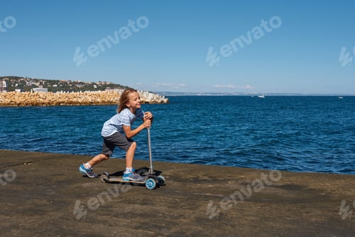 Preview: Boy riding a scooter on a pier at sunny day