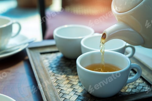 Preview: Tea pour from a white jug.Glass tea placed in a wooden tray.