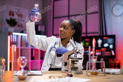 Preview: Positive smart enthusiastic african american woman scientist looking at the test tubes.