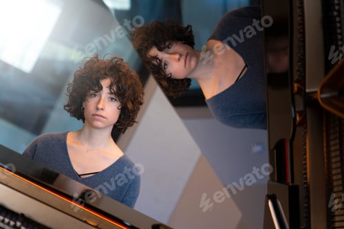 Preview: Young woman with curly hair sitting at a grand piano thinking and playing