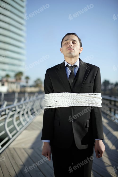 Preview: Business man tied up with ropes outdoors