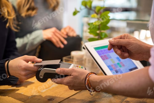 Preview: Female customer in shop, paying for goods using credit card on contactless payment machine, mid