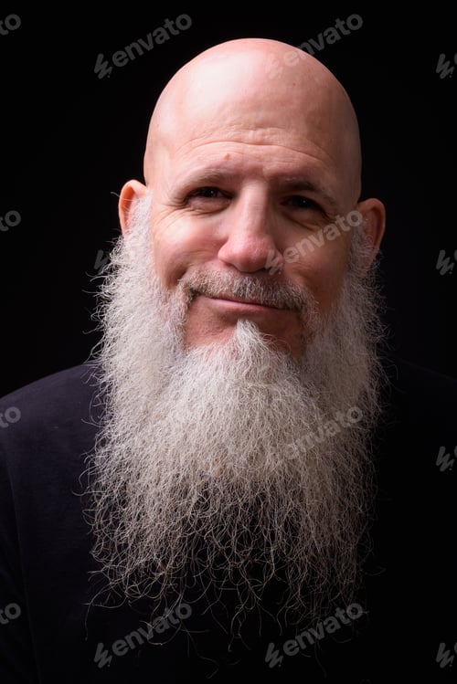 Preview: Mature bald bearded man against black background