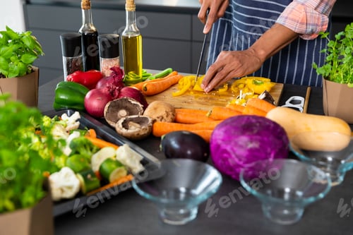 Preview: Midsection of biracial man wearing apron preparing meal, chopping vegetables in kitchen, copy space
