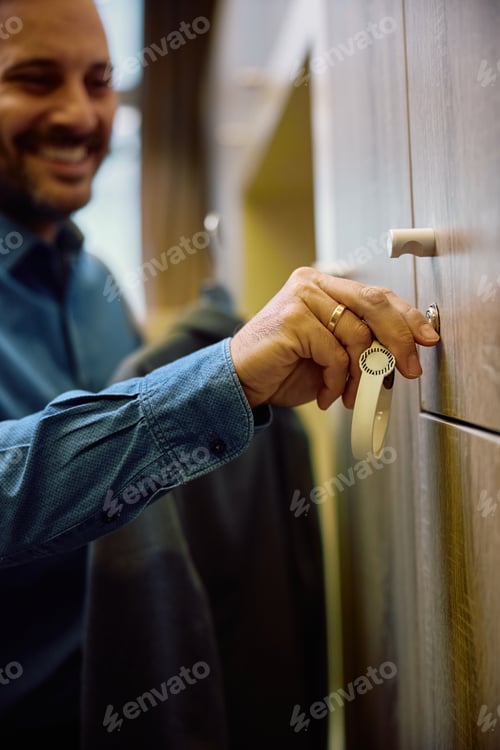 Preview: Close up of businessman using locker in dressing room at health club.
