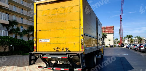 Preview: Large yellow truck parked at building making deliveries.
