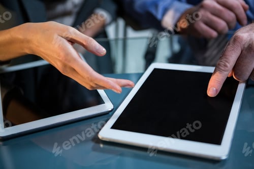 Preview: Close-Up Of Businessman Discussing With Colleague Over Digital Tablet In The Office