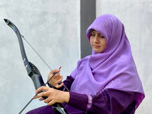 Preview: Hijab young woman sitting and preparing archery set