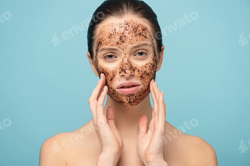 Preview: beautiful girl applying coffee scrub on face, isolated on blue