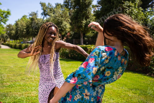 Preview: Two women of different ethnicities dancing energetically outdoors