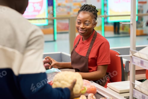 Preview: Happy young black woman in uniform serving male customer in supermarket