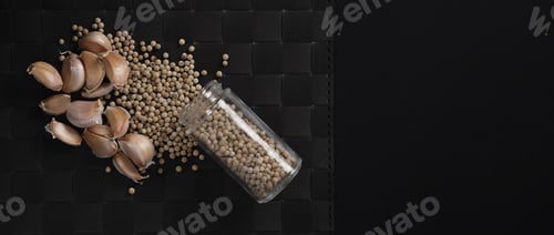 Preview: Garlic and pepper. Natural Garlics and white peppercorn in glass bottle on plate mat black backgroun