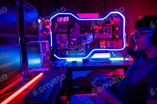 Preview: Young Asian man gamer wearing glasses and headphones playing a video game on modern gaming pc