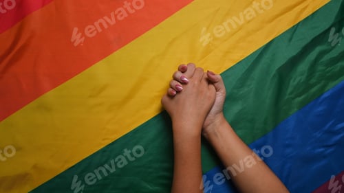 Preview: Young asian women LGBT lesbian couple holding hands over LGBT pride flag.