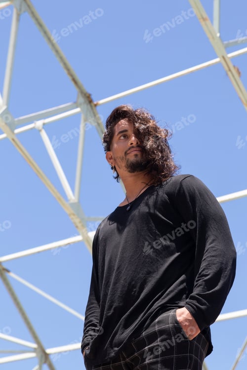 Preview: Young hispanic latin street dancer with blue sky background and metal structure