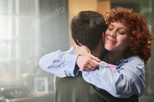 Preview: Young Adult Woman Hugging Man While Holding Positive Pregnancy Test