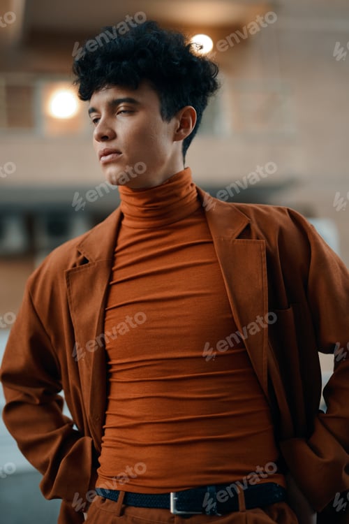 Preview: Stylish young man in a brown outfit with a turtleneck, against a blurred urban background