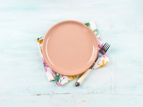 Vista previa: Mesa primavera-verano con plato rosa, tenedor y servilleta floral sobre fondo turquesa.