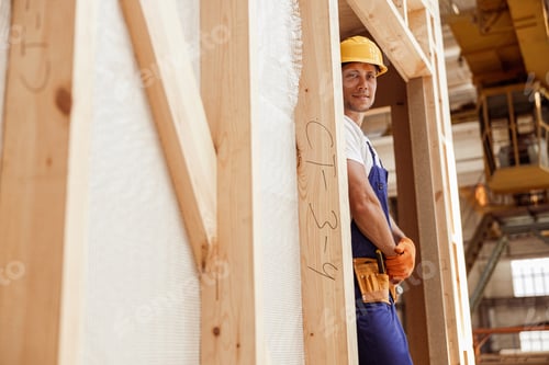 Preview: Smiling male worker standing inside wooden construction cabin